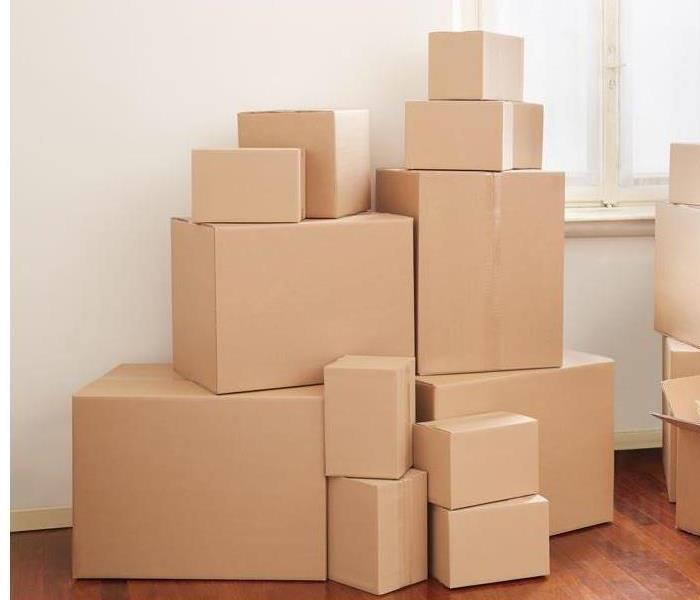 small and big plain brown moving boxes stacked up on top of each other on top of a wooden floor next to a window