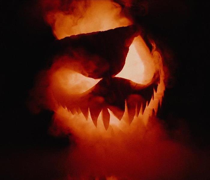 Smoke and flames surrounding a carved pumpkin.