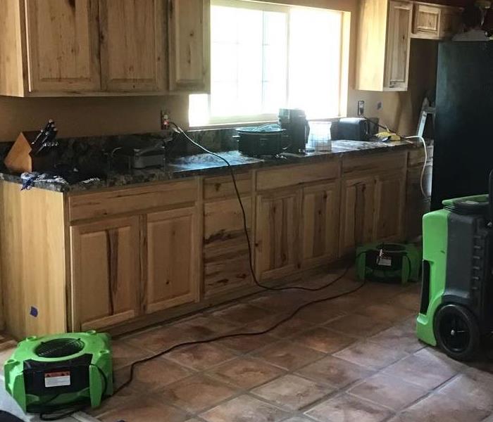 wooden kitchen cabinents with two green SERVPRO equipment